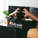 Homem com camisa do Bitcoin desesperado olhando gráfico de preço