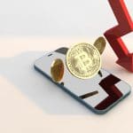 Bitcoin e seta de preço em queda em cima de celular