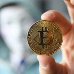 Hacker usando máscara e segurando Bitcoin desconhecido