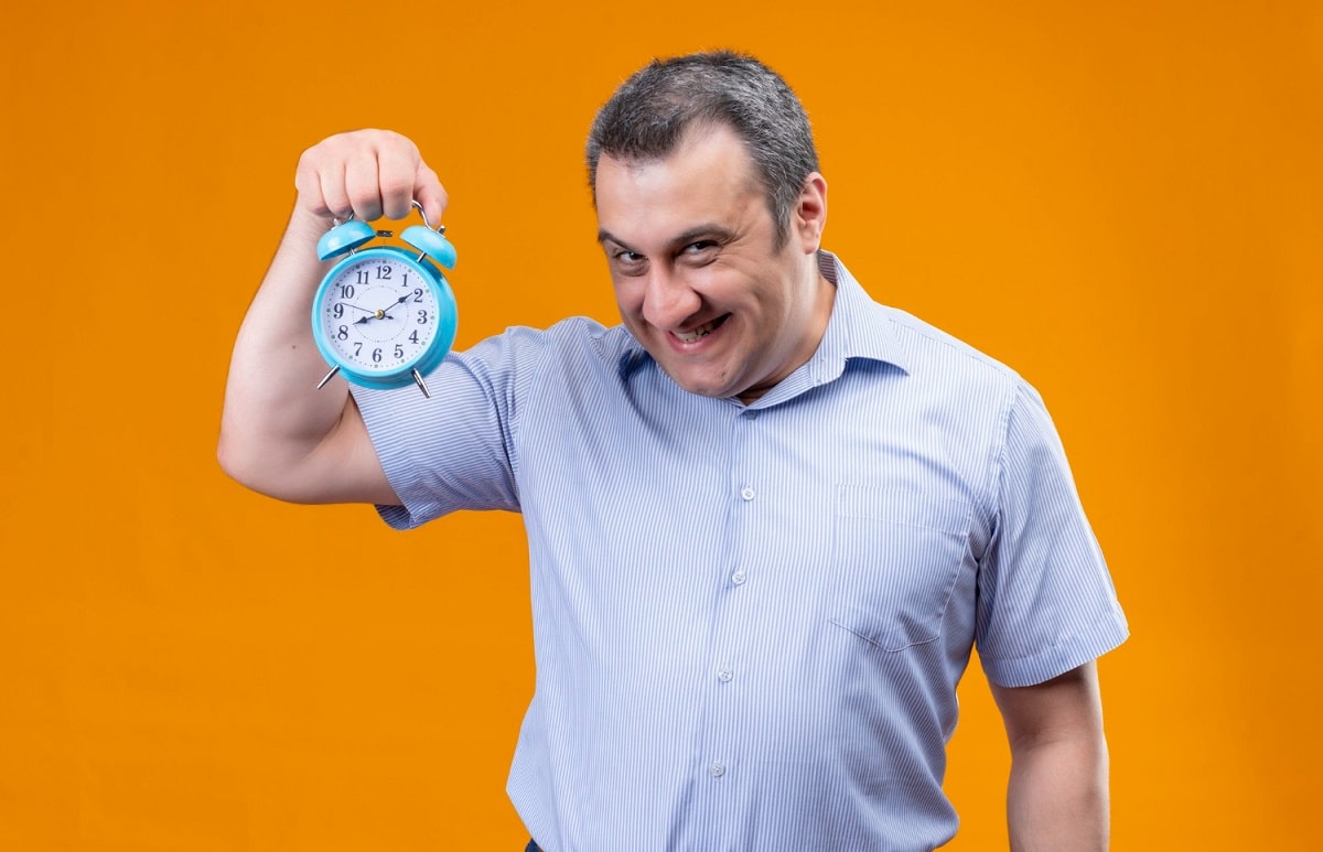 Homem engraçado segurando despertador