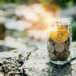 Bitcoin em cima de outras moedas em um pote