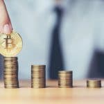 Mão segurando Bitcoin em pilha de moedas
