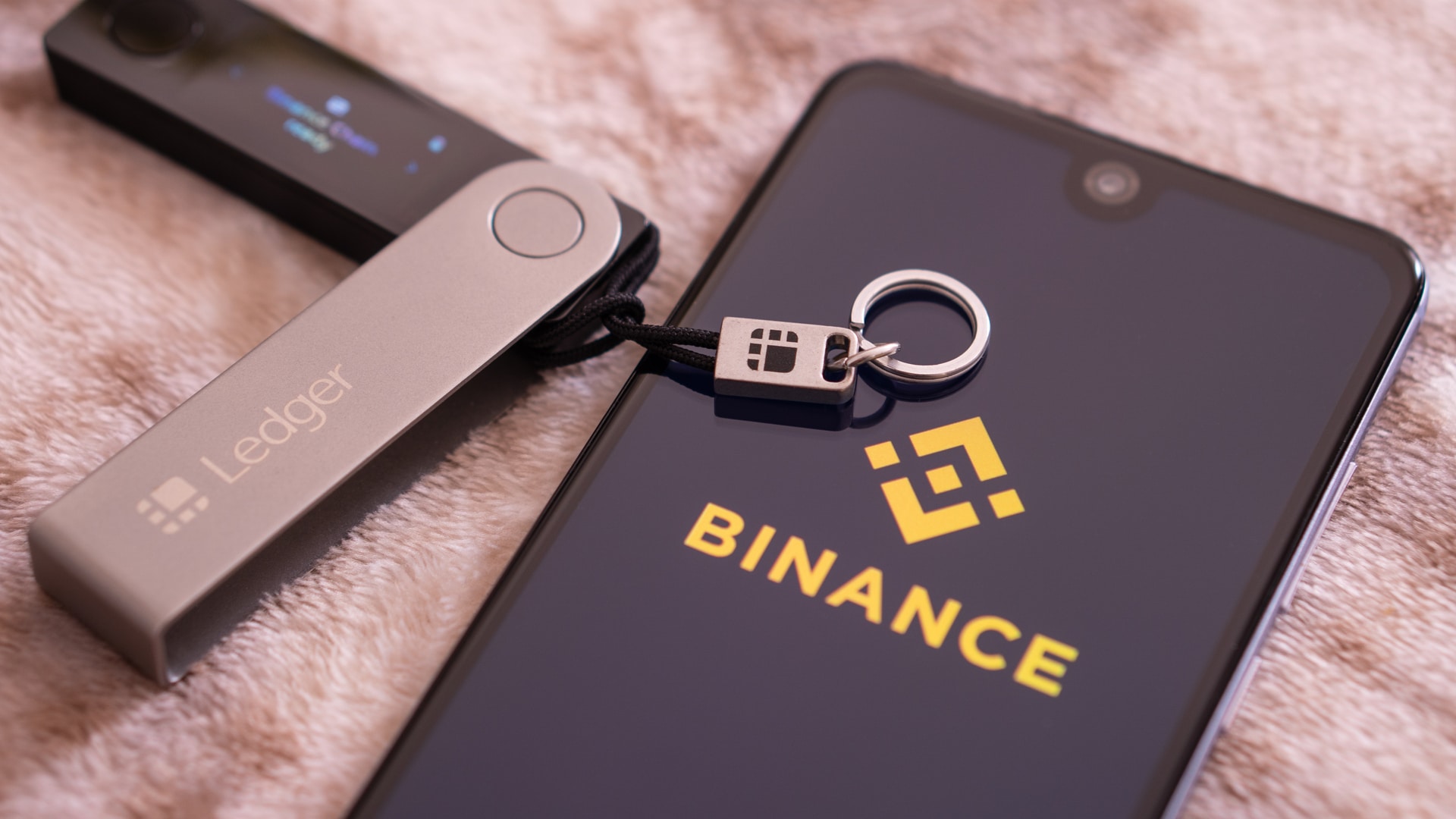 Aplicativo da corretora Binance ao lado de uma carteira ledger