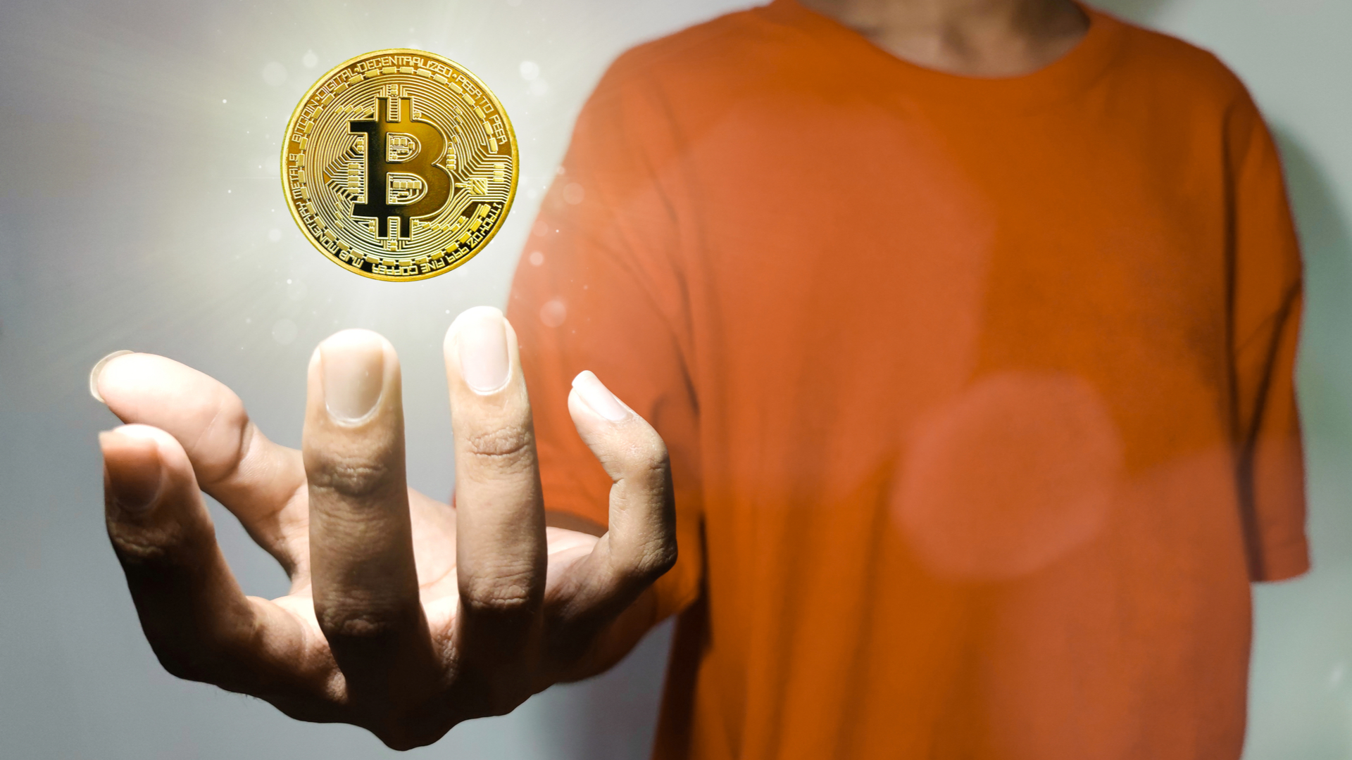 Jovem segurando Bitcoin virtualmente