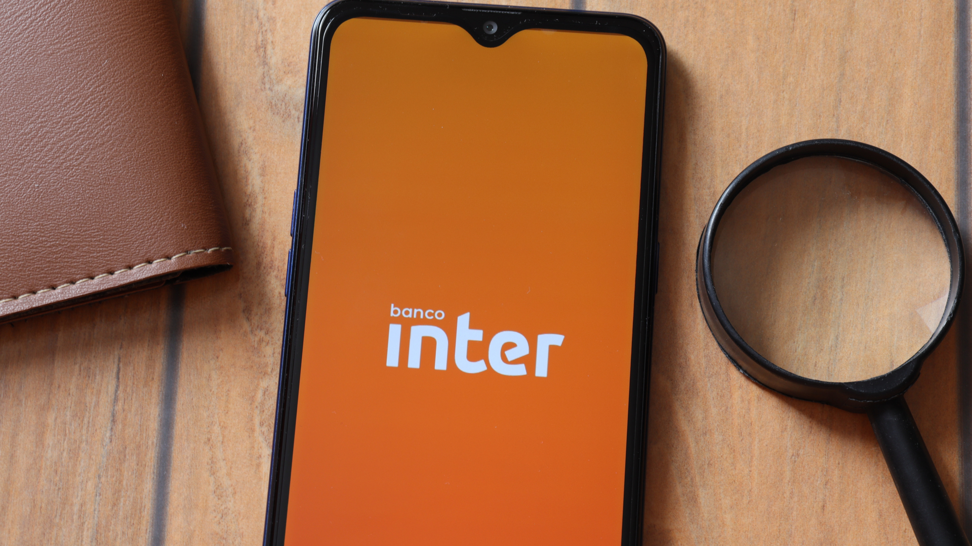 Banco Inter em tela de celular ao lado de lupa