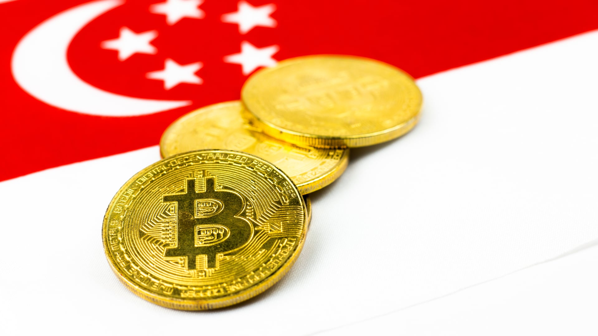 Moedas de Bitcoin sobre bandeira de Singapura alerta
