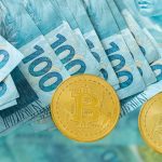 Notas de 100 reais e moedas de Bitcoin Brasil brasileiros