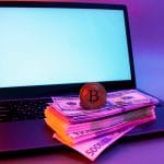 Notebook com pilha de dinheiro e Bitcoin em cima ransomwares