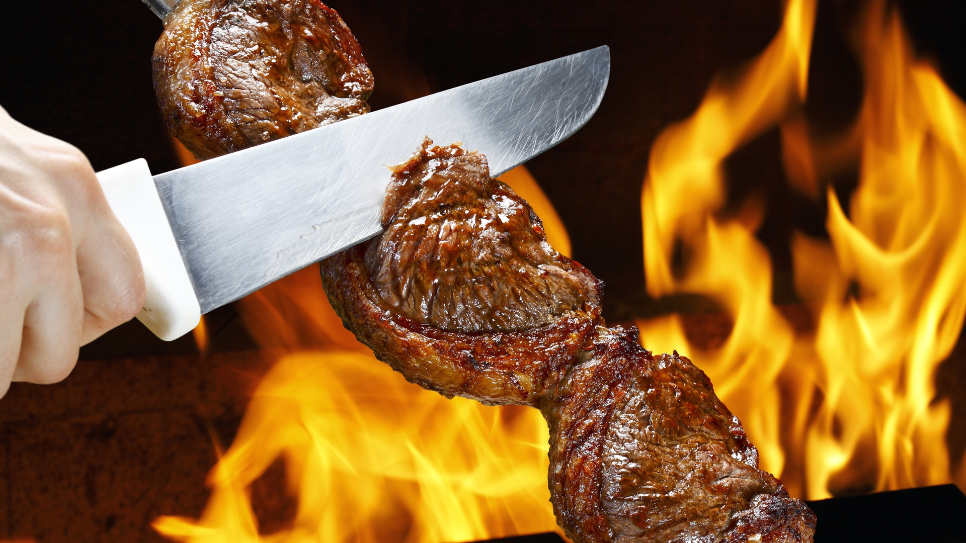 Pessoa cortando picanha enquanto fogo pega atrás Faraó