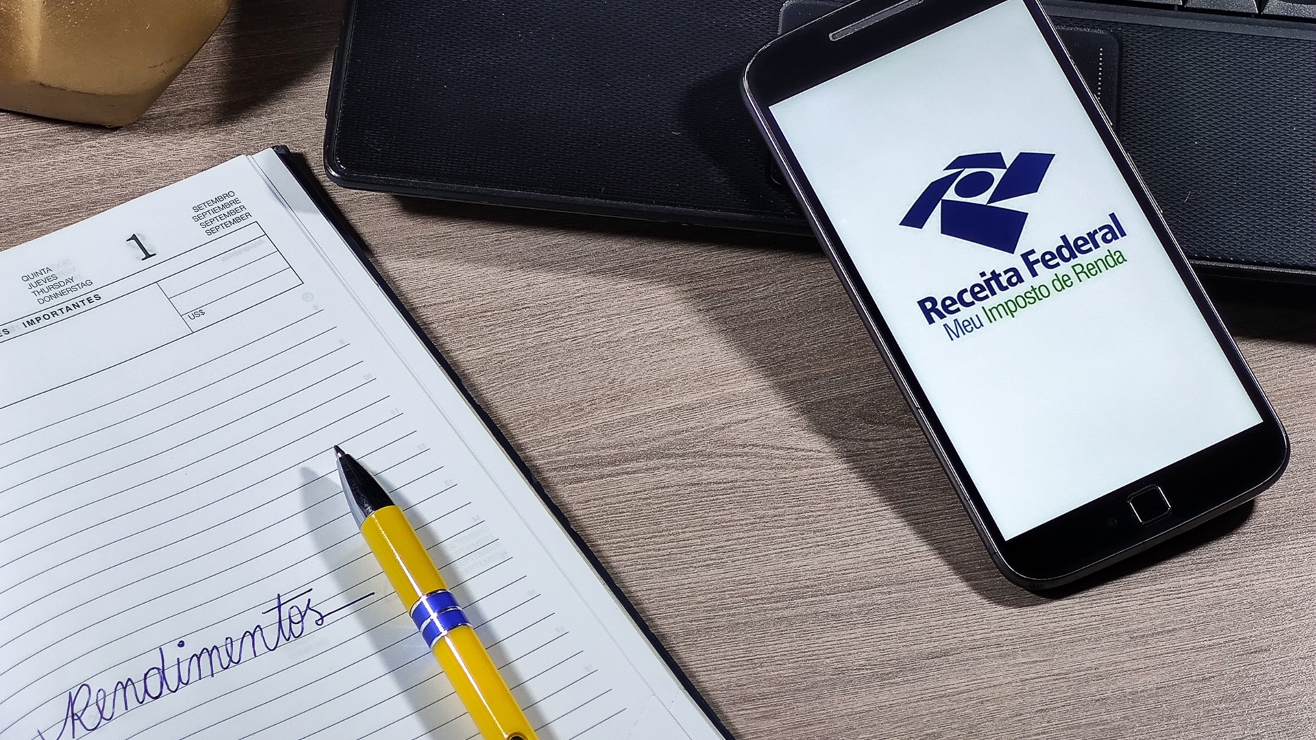 Aplicativo da Receita Federal do Brasil e caderno com a palavra Rendimentos