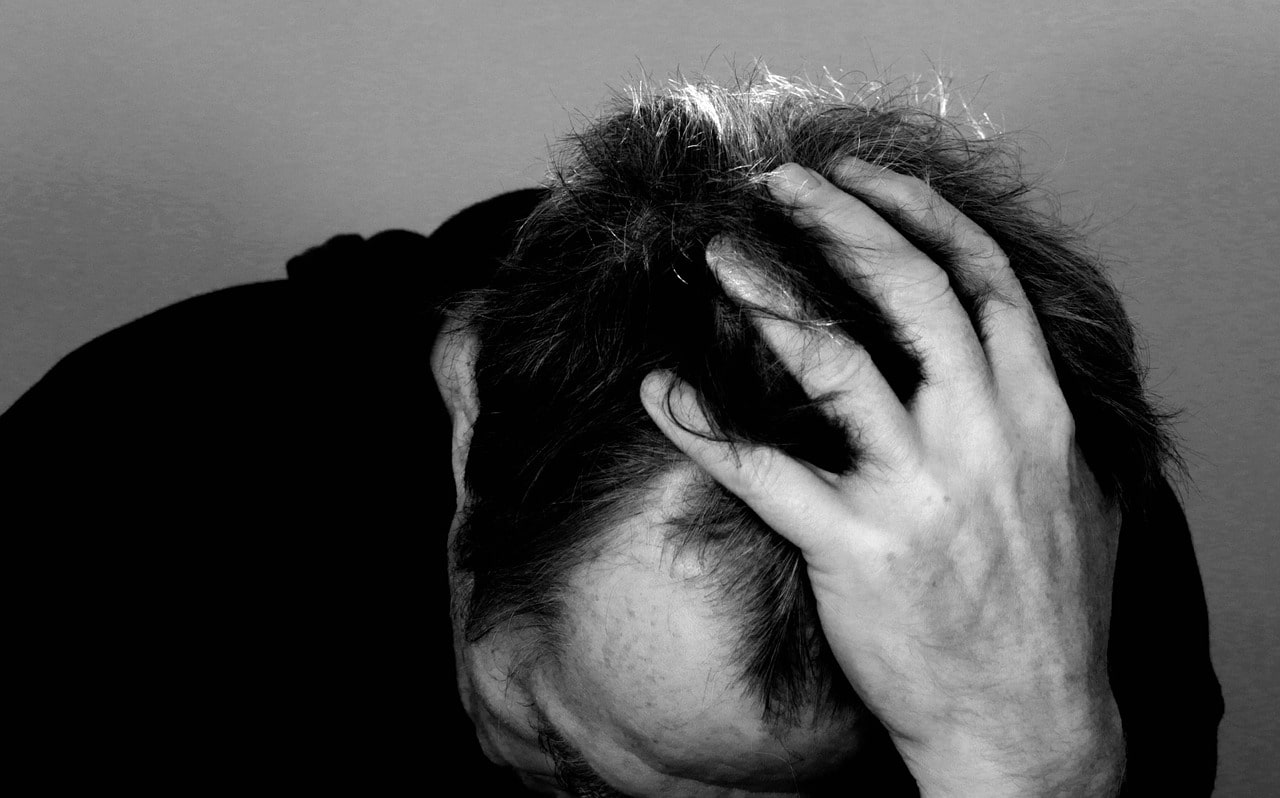 Homem desesperado com mão na cabeça