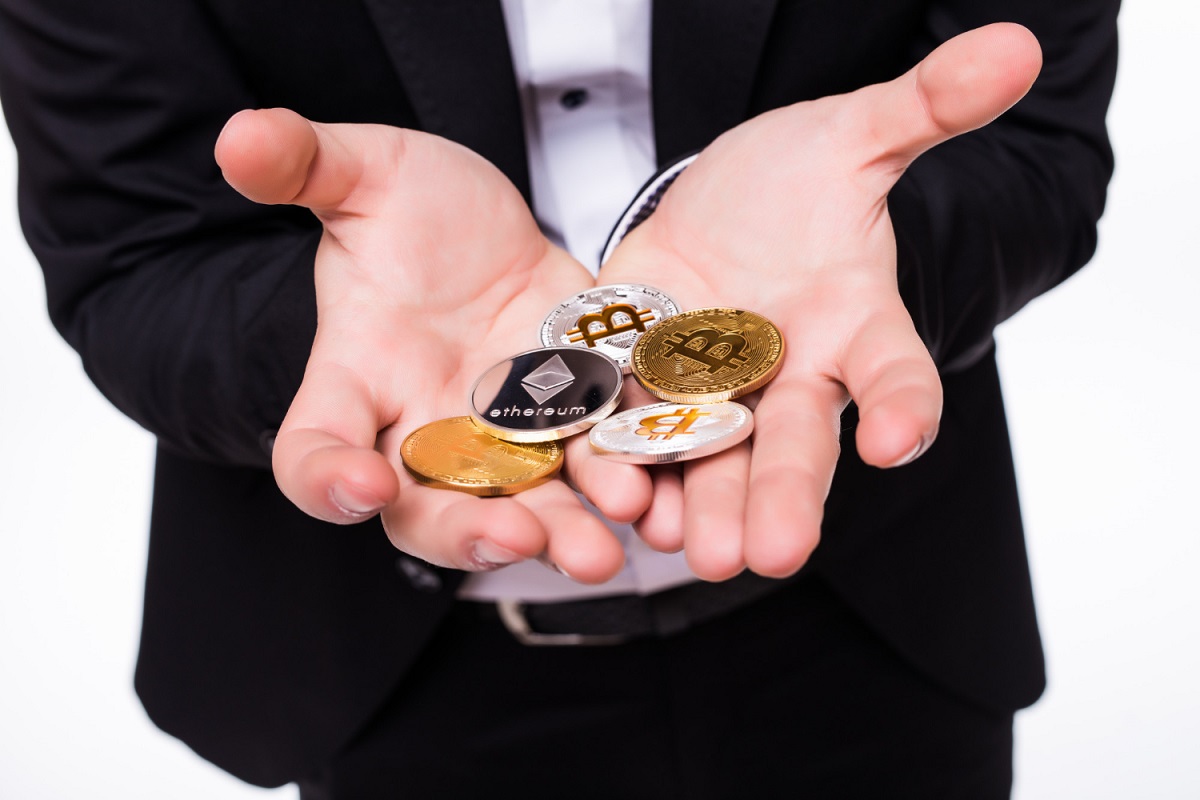 Homem segurando criptomoedas em mão