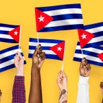 Mãos em Cuba segurando bandeiras com fundo laranja Bitcoin