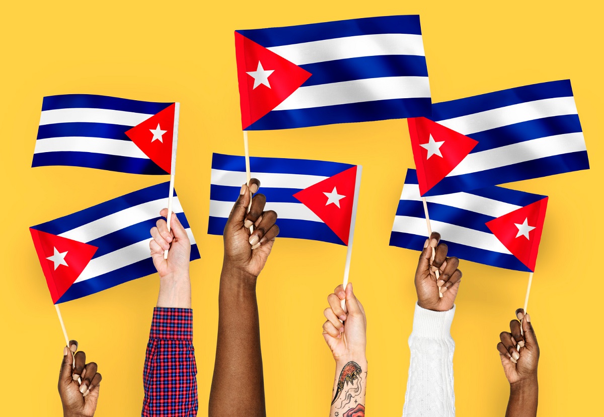 Mãos em Cuba segurando bandeiras com fundo laranja Bitcoin