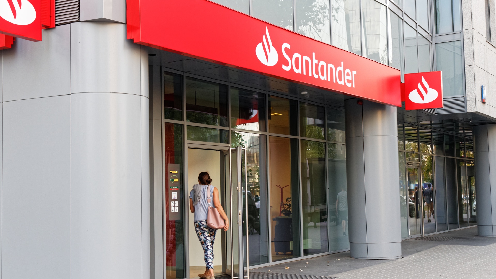 Mulher entrando em agência do Banco Santander na Varsóvia, Polônia