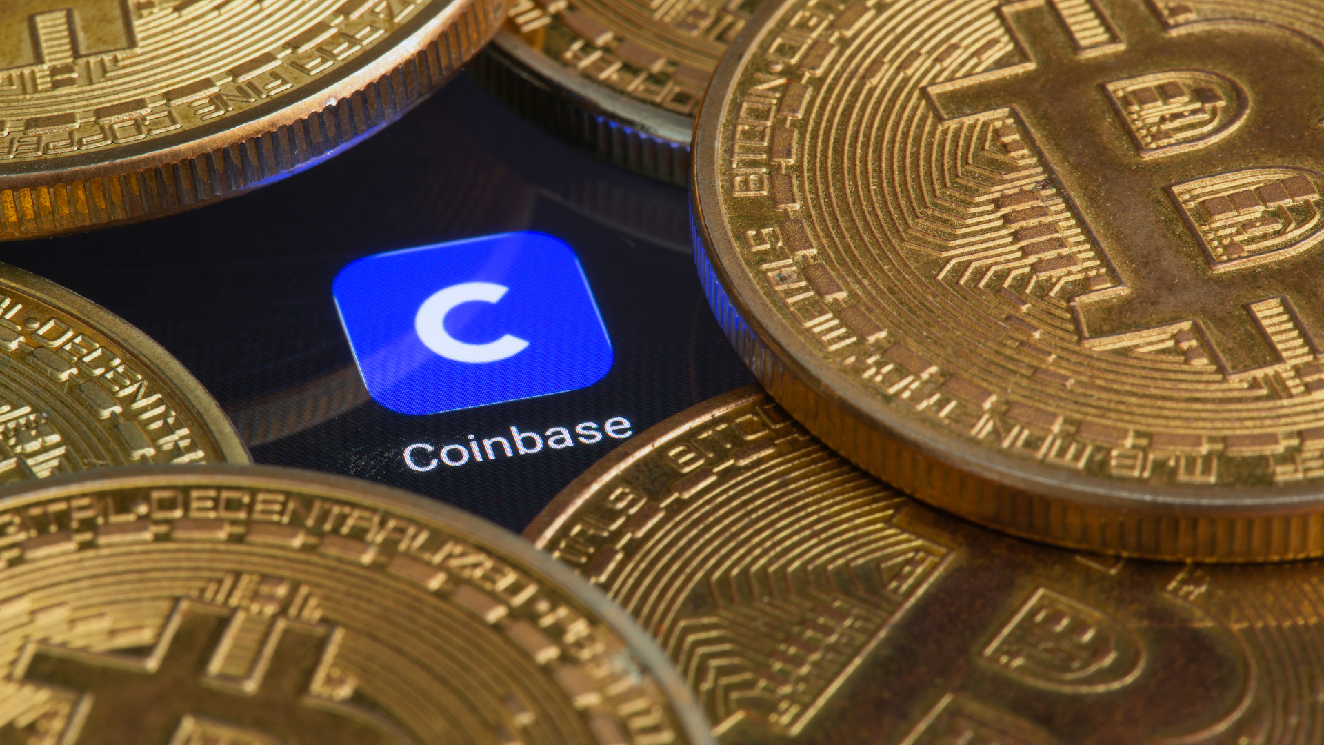 Símbolo da corretora Coinbase em meio a Bitcoins