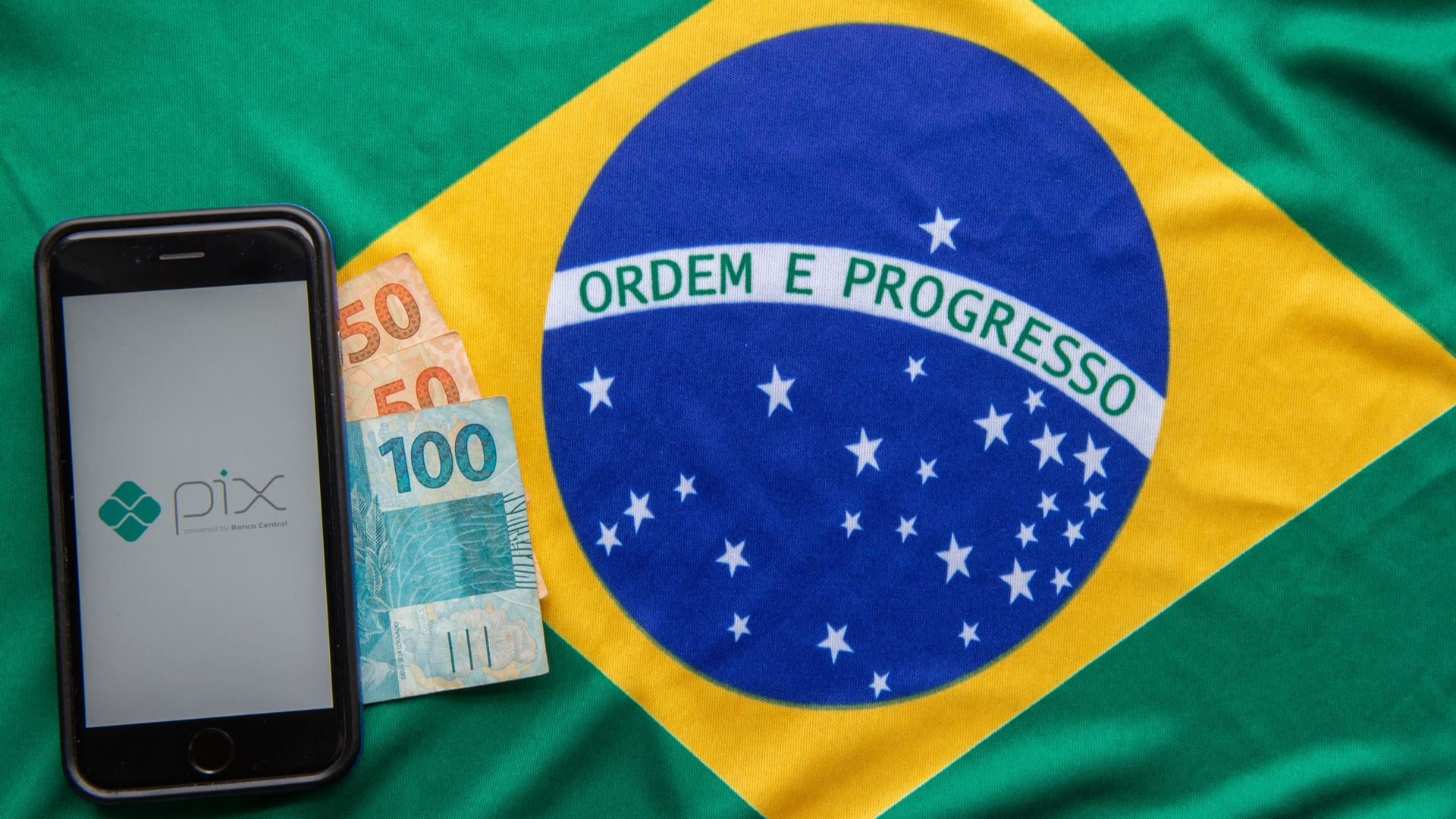 Aplicativo do PIX, notas de Real brasileiro e bandeira do Brasil