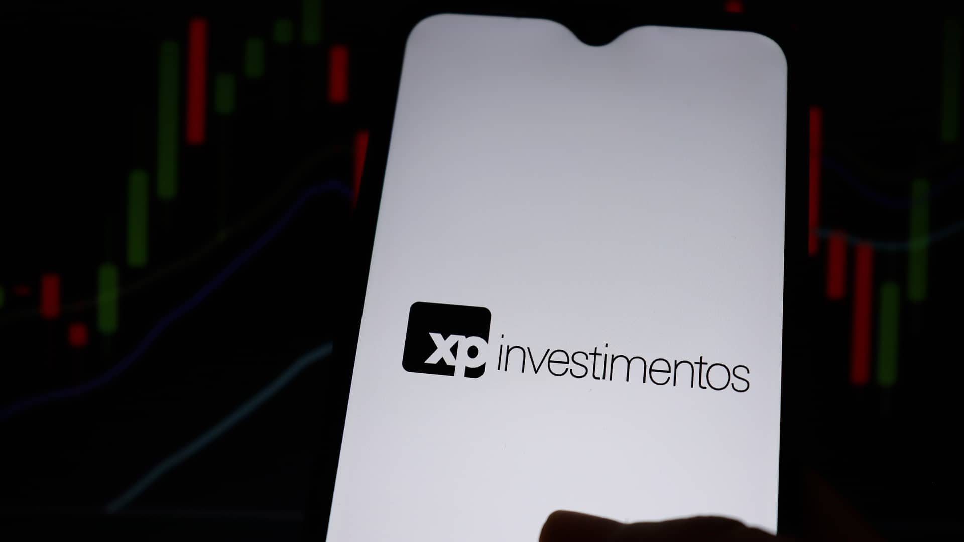 XP Investimentos e gráficos ao fundo