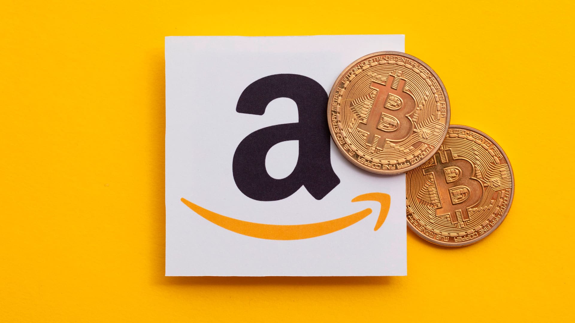 Logo da Amazon e criptomoeda física de Bitcoin