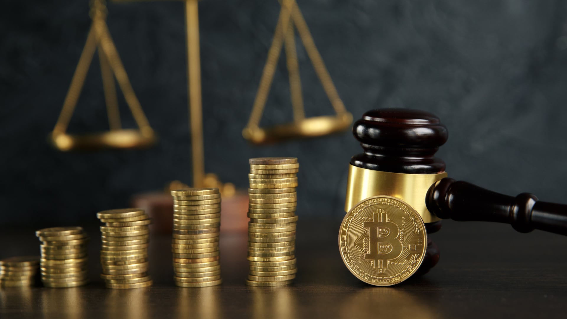 Martelo e balança da justiça próximo de pilhas de Bitcoins
