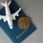Miniatura de avião, passaporte e Bitcoin