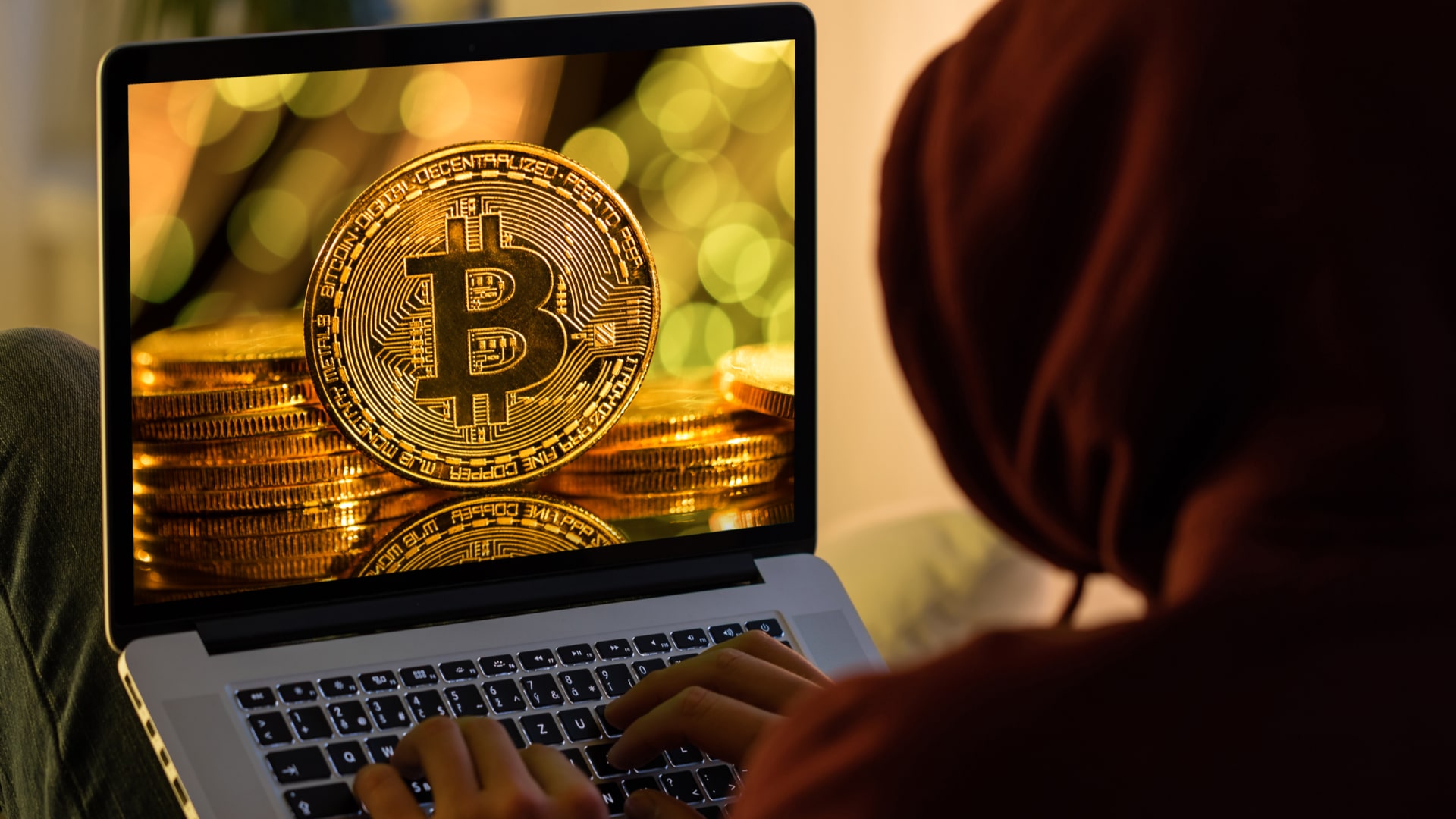 Moeda de Bitcoin e hacker anônimo sentado com laptop
