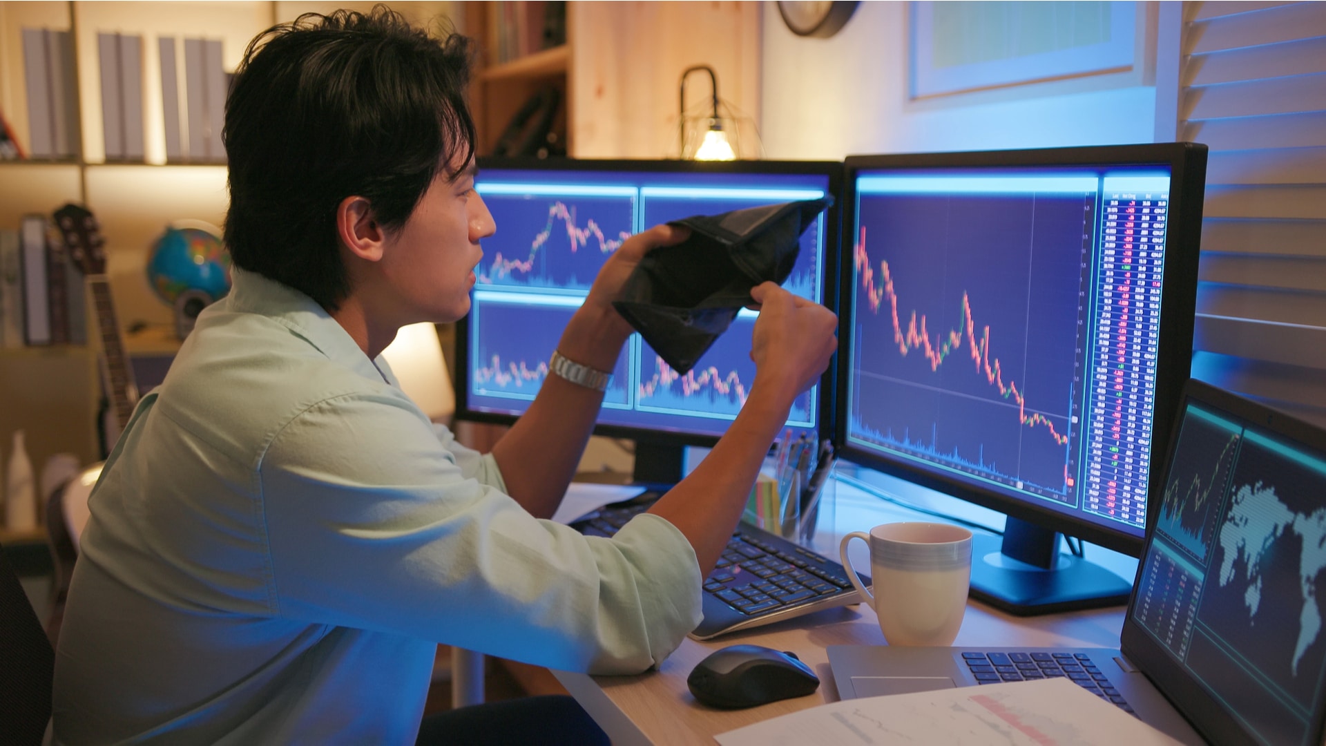 Homem com a carteira vazia em frente a gráficos de criptomoedas