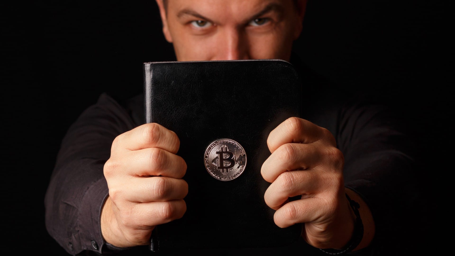 Homem segurando livro com imagem do Bitcoin colada nele pastor