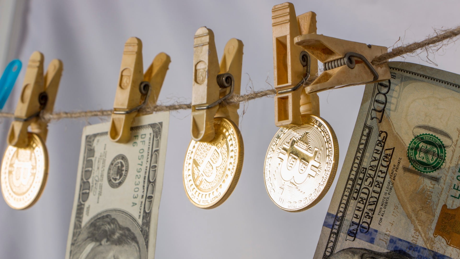 Varal com notas de Dólar e Bitcoin pendurados