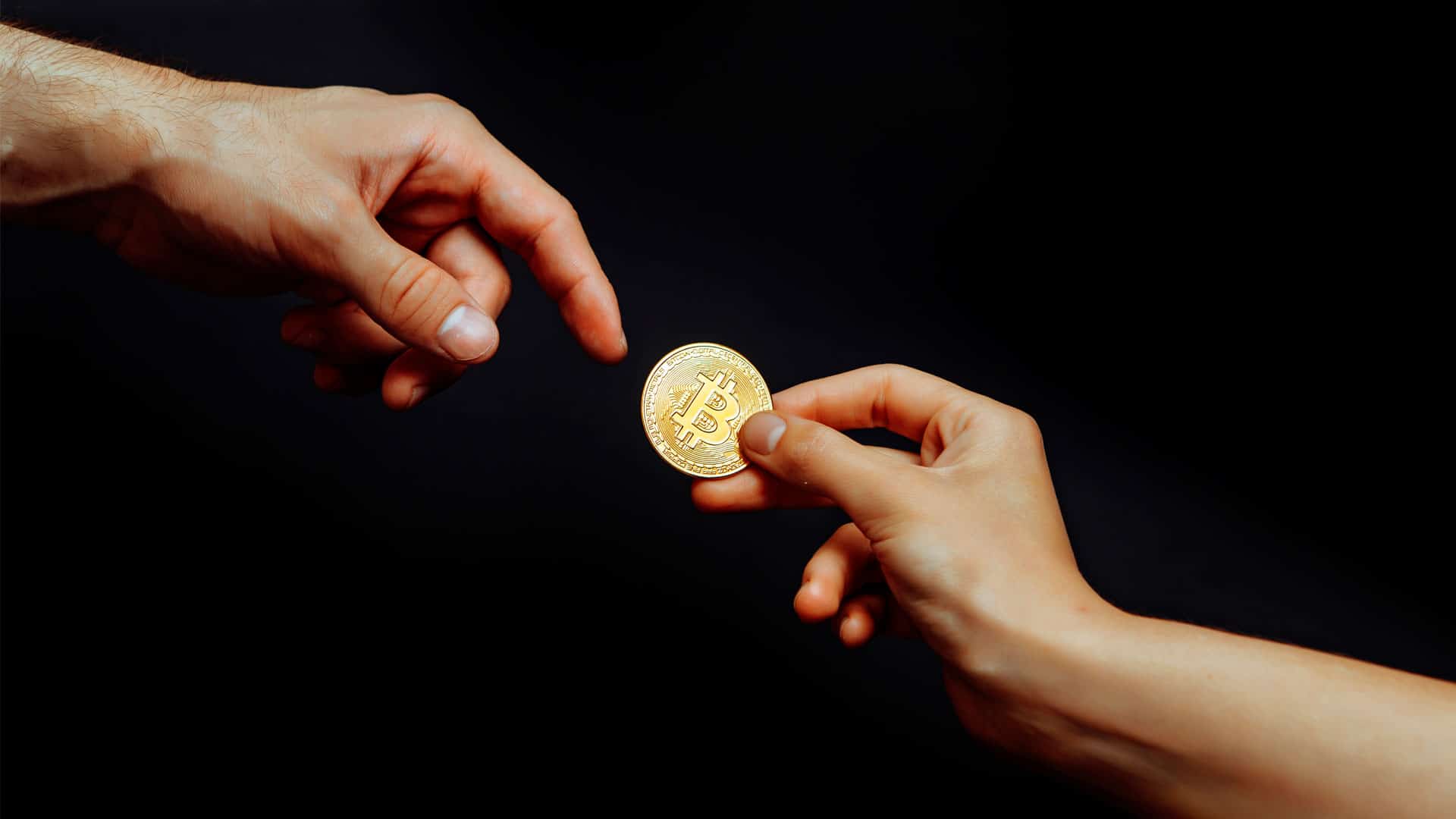 Moeda física de Bitcoin sendo passada para outra pessoa.
