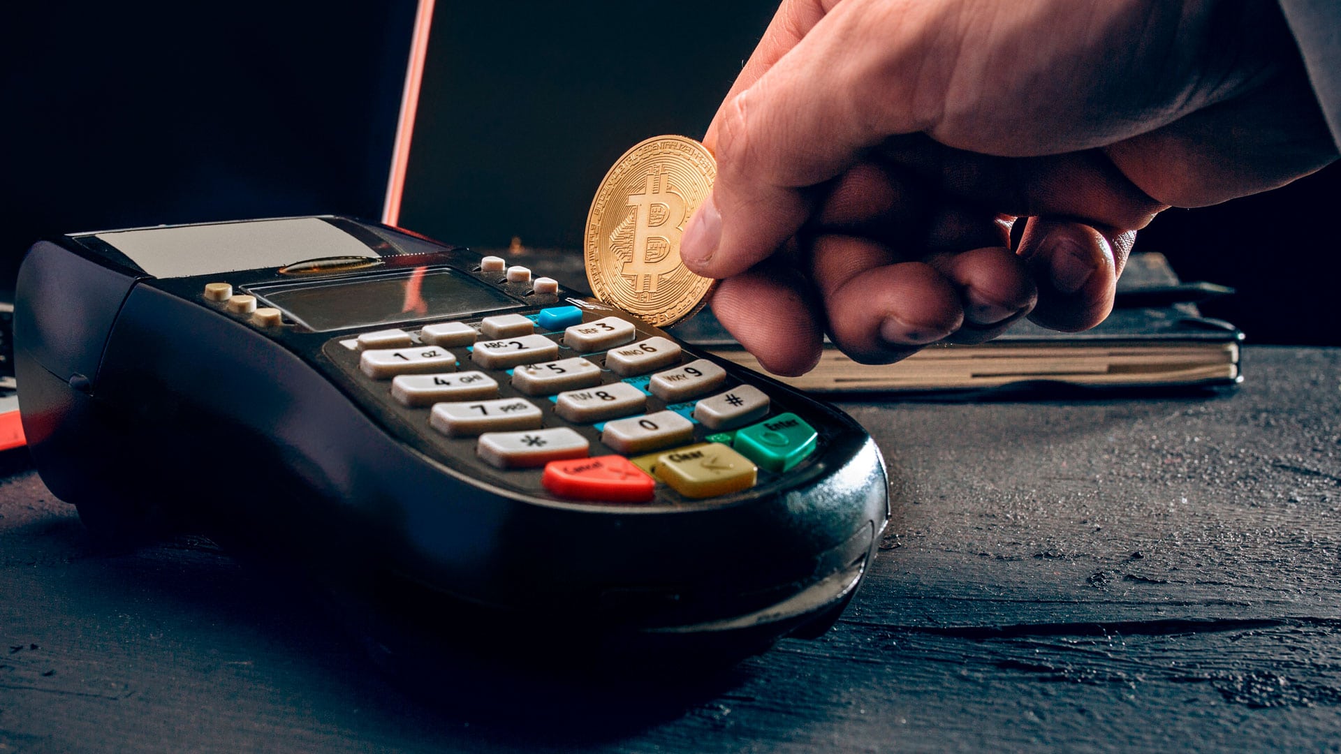 Moeda de Bitcoin sendo passada em máquina de cartão.