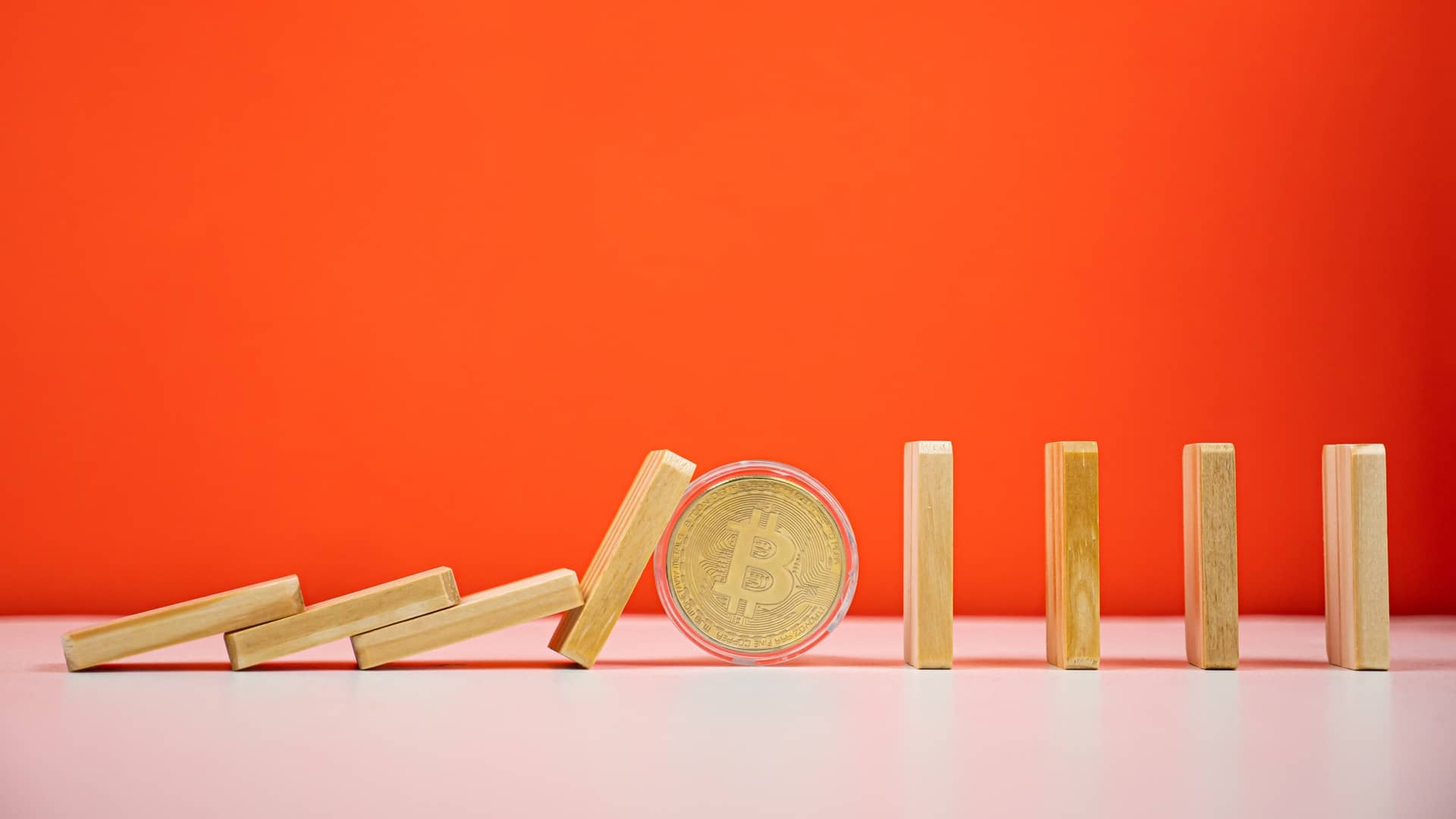 O efeito dominó parado por bitcoin forte em fundo laranja