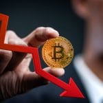 Homem segurando moeda de Bitcoin (BTC) e seta apontando queda do mercado.