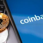Logo da Coinbase em celular, ao lado de criptomoedas Bitcoin e Ethereum.