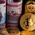 Moedas físicas de Bitcoin ao lado de rublos da Rússia e matrioskas.