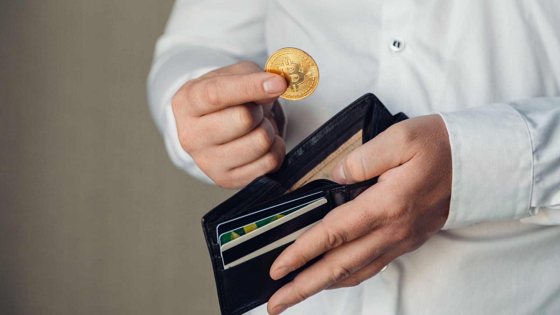 Mãos de um trabalhador colocando bitcoin em uma carteira vazia
