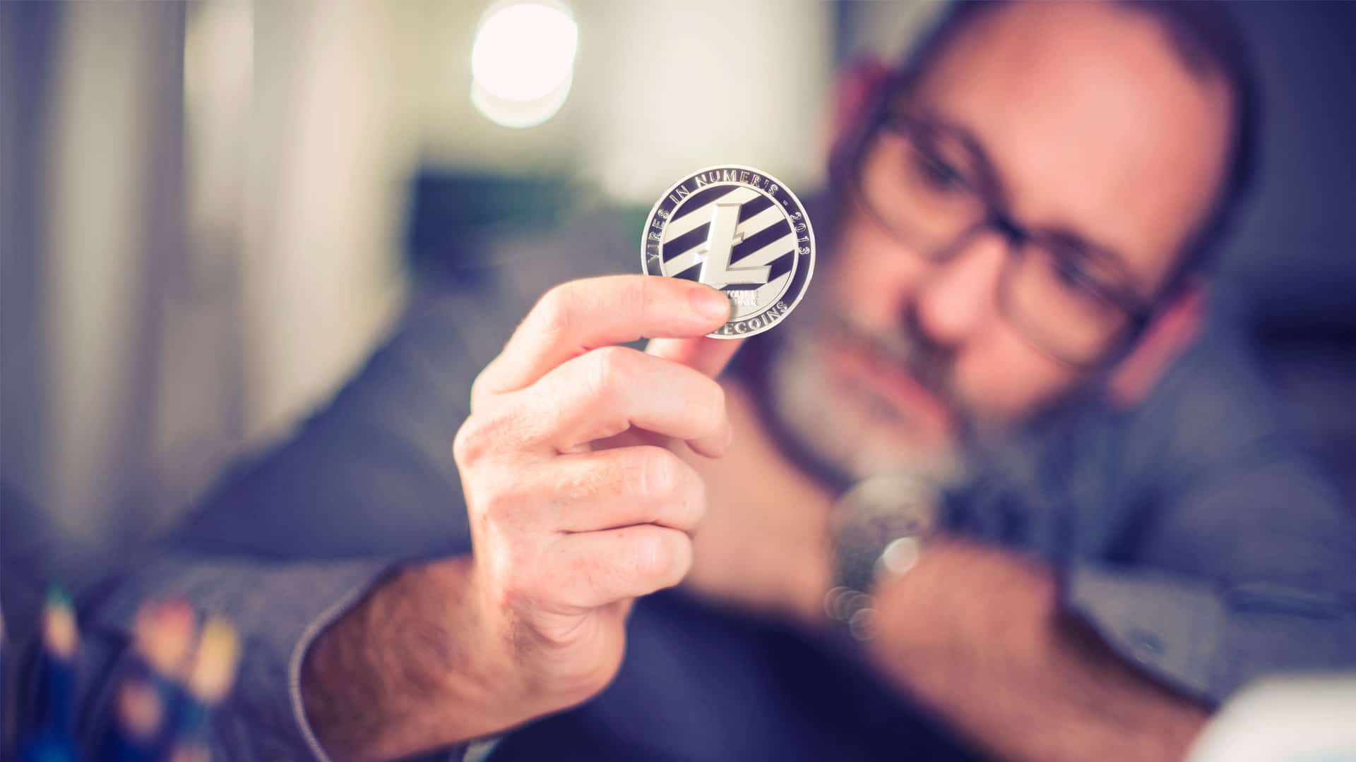 Investidor segurando moeda física de Litecoin (LTC).