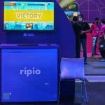 Estande da Ripio no Big Festival 2022, com jogo em televisão indicando vitória