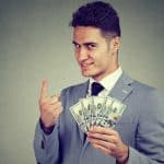 Trader com notas de dinheiro na mão e olhar ganancioso