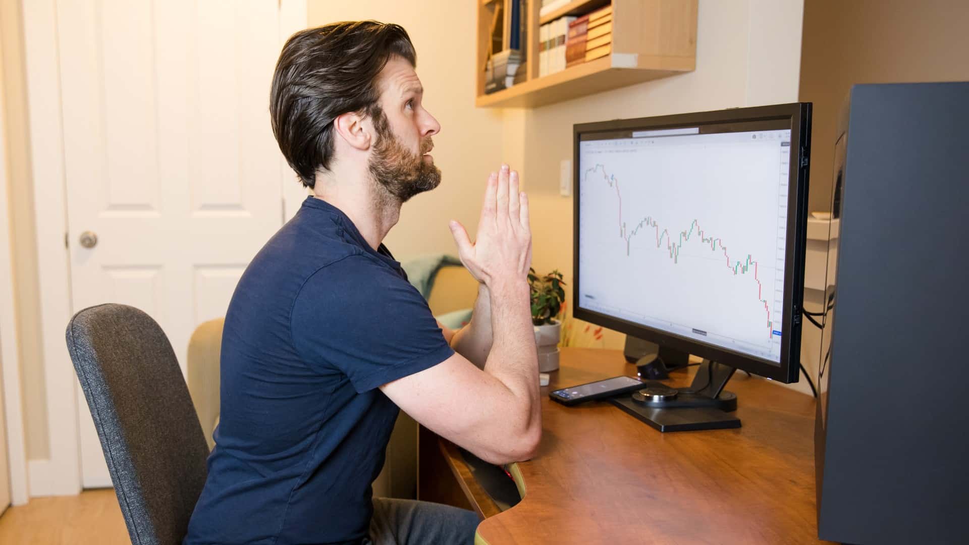 Trader de Bitcoin torcendo por sucesso de negociação com gráficos em queda