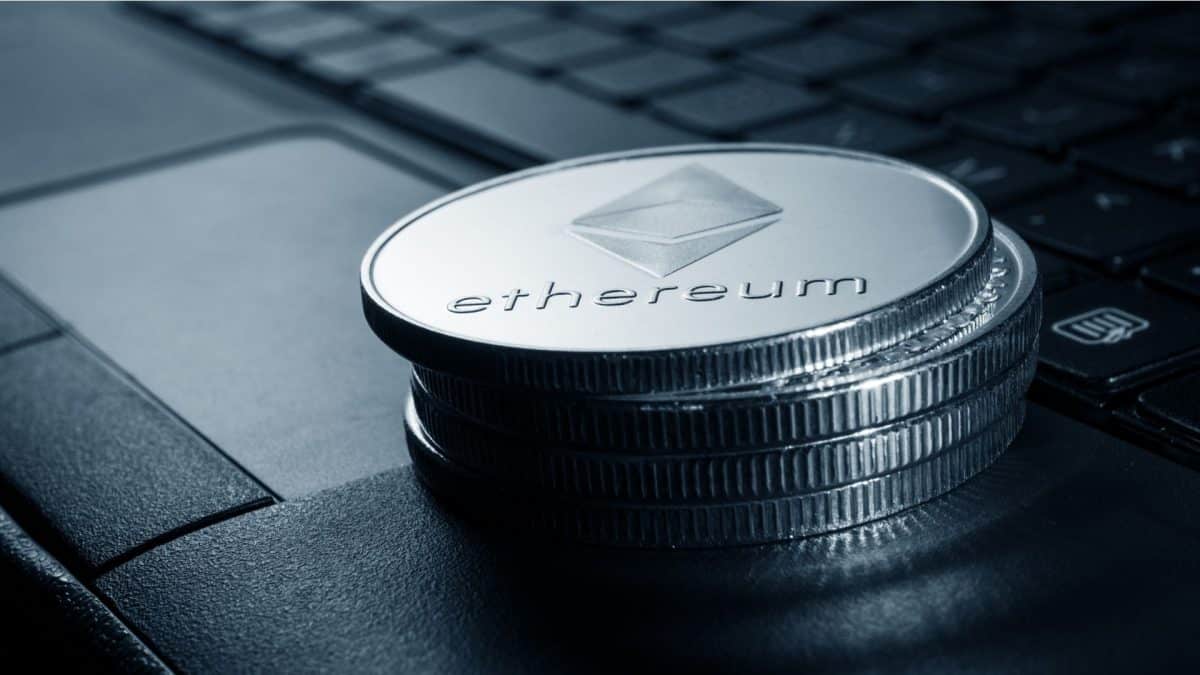 Pilha de moedas físicas de Ethereum sobre notebook.