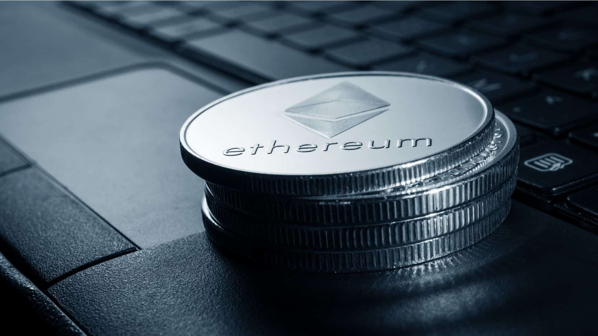 Pilha de moedas físicas de Ethereum sobre notebook.