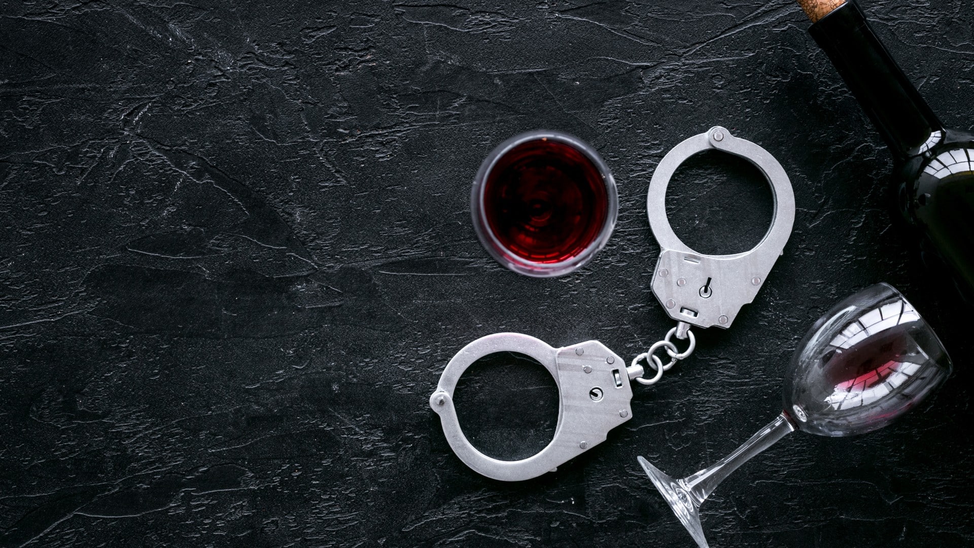 Algemas da polícia próximo de garrafa e taças de vinho