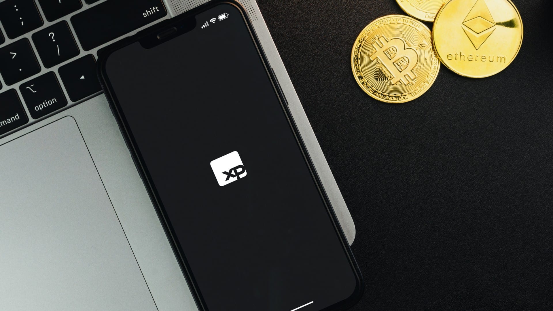 Aplicativo da XP Investimentos ao lado de Bitcoin e Ethereum