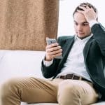 Homem preocupado com mão na cabeça ao ler notícias