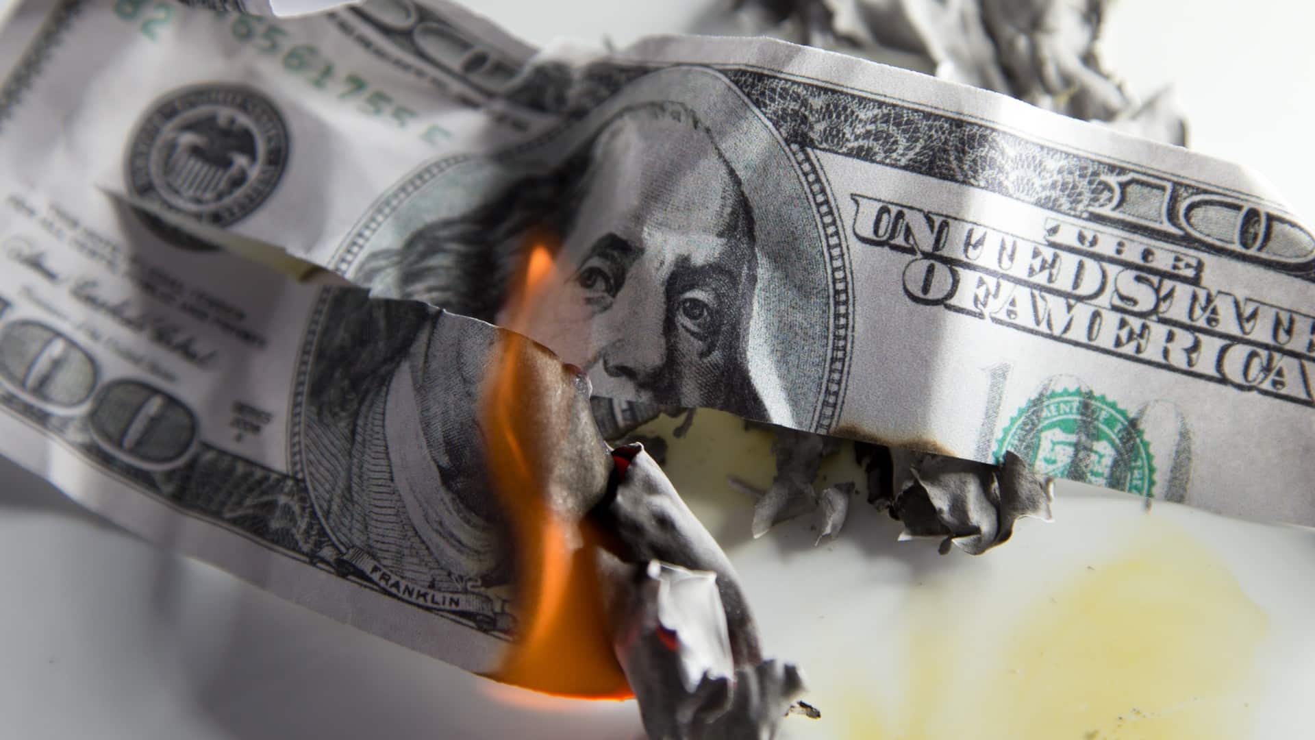 Nota de Dólar pegando fogo e rasgada