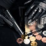 Bandido armado acessando cofre com moedas de Bitcoin.