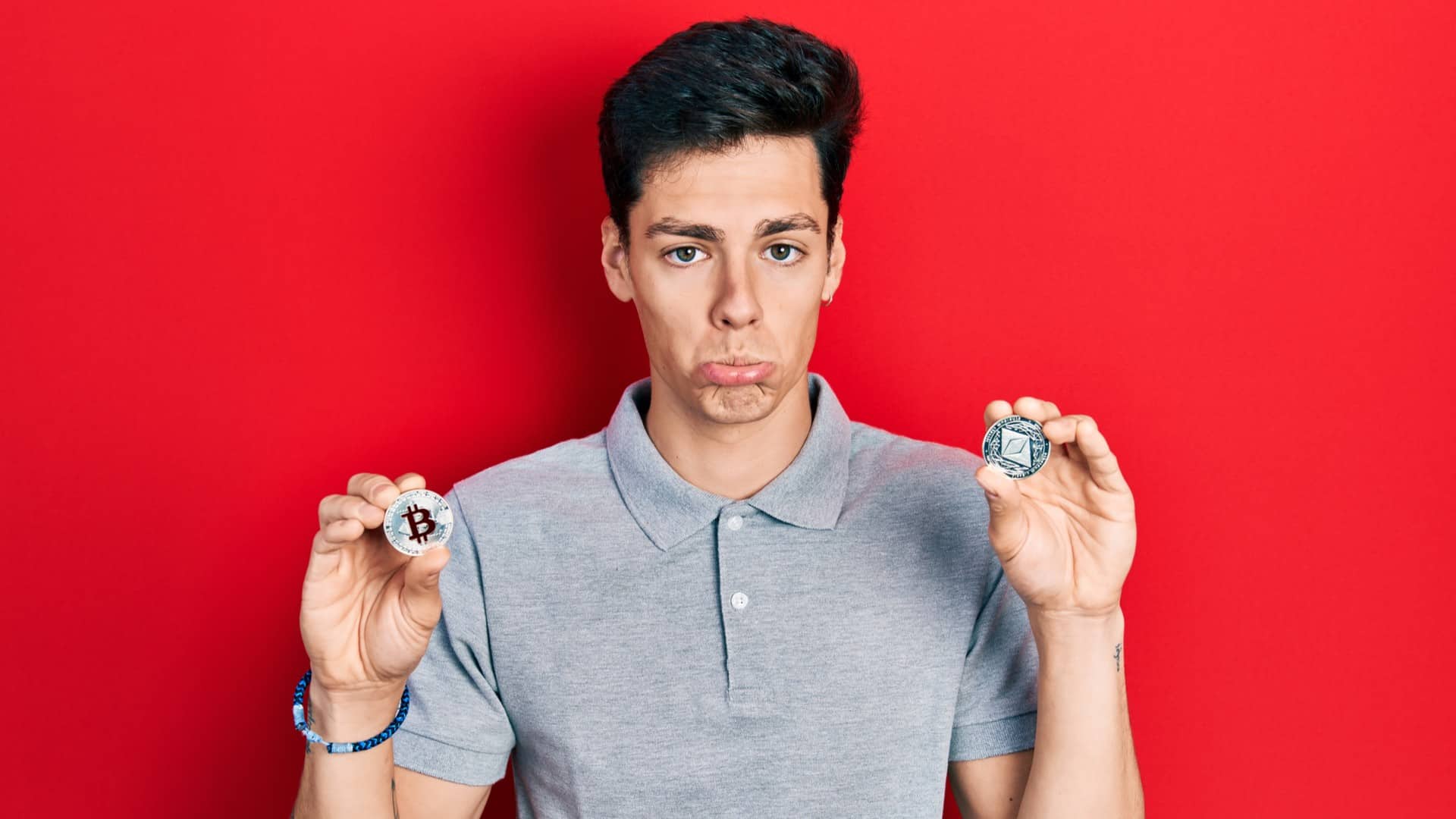 Homem depressivo segurando bitcoin e ethereum, criptomoedas famosas