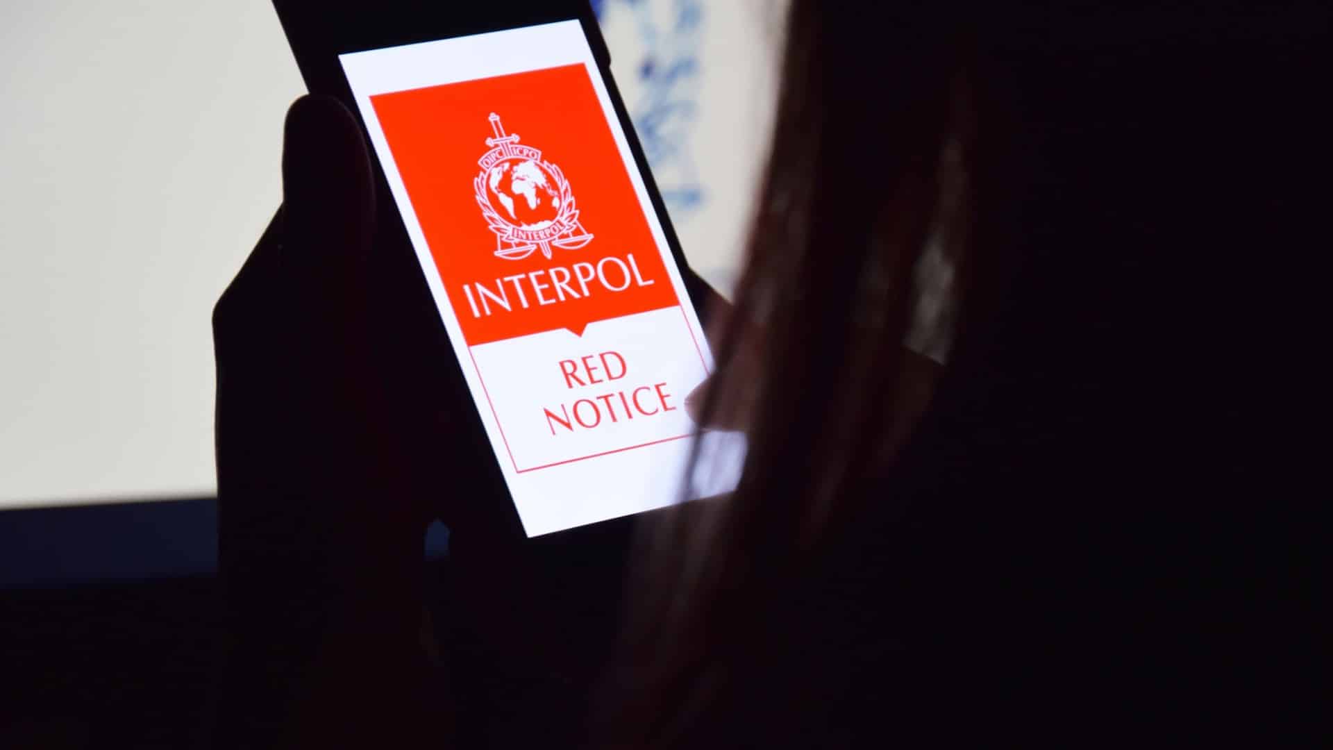 Mulher observando aplicativo da lista vermelha da Interpol