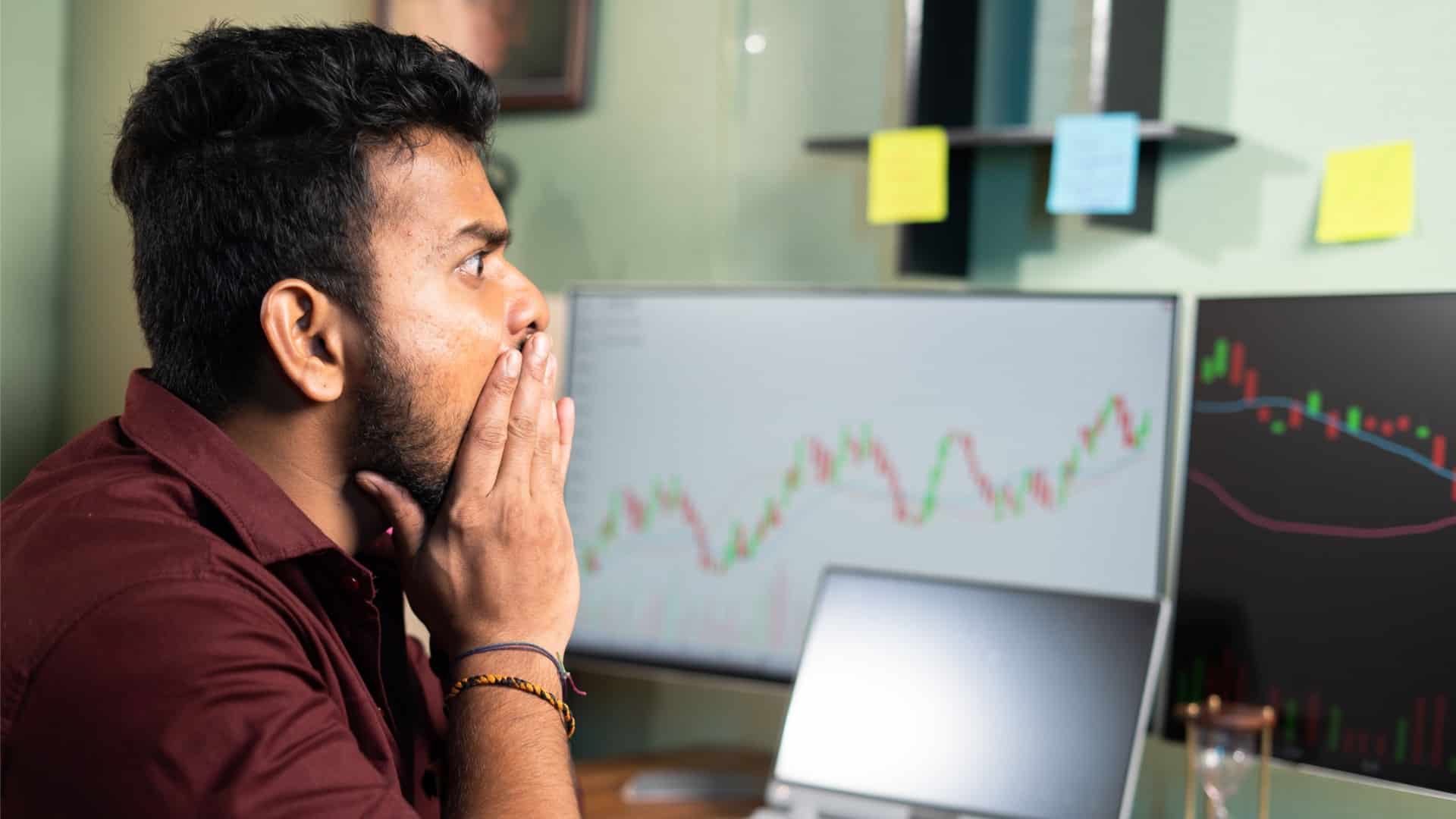 Trader de criptomoedas preocupado ao olhar para tela de corretoras